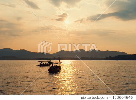 Evening scenic view of West Lake with tourists in boats during sunset Evening scenic view of West Lake with tourists in boats during sunset 133604646