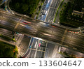 Aerial view of a busy highway intersection at night in an urban area, with moving car light trails. 133604647