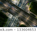Aerial view of a busy highway intersection at night in an urban area, with moving car light trails. 133604653