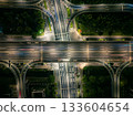 Aerial view of a busy highway intersection at night in an urban area, with moving car light trails. 133604654