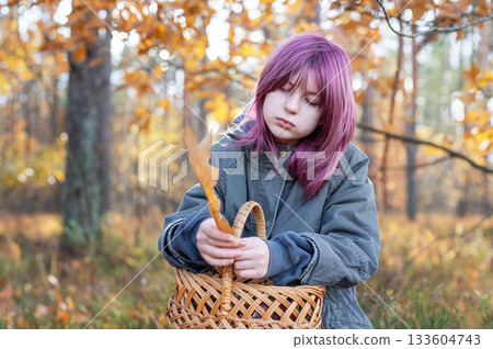 Thoughtful girl with pink hair holding autumn leaf in forest Thoughtful girl with pink hair holding autumn leaf in forest 133604743