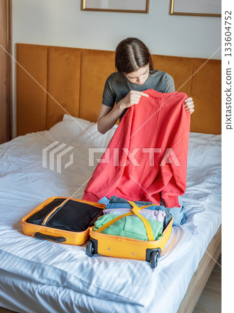 Woman packing clothes for travel trip preparing suitcase 133604752