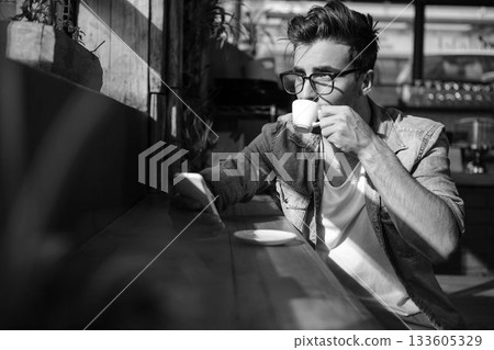 Man using mobile phone while having cup of tea 133605329
