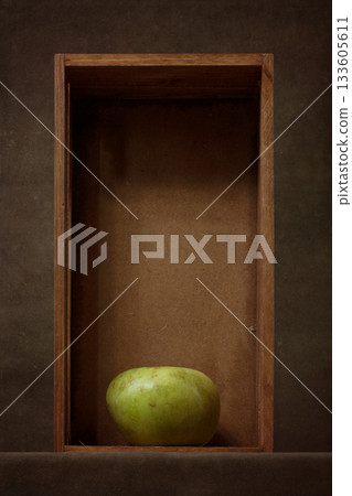 Still life with a green apple in a wooden box 133605611