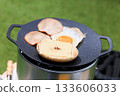 Close-up of a black multi-griddle and ingredients, with grass green in the background 133606033