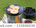 Close-up of a black multi-griddle and ingredients, with grass green in the background 133606036