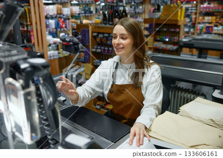 Cute woman cashier at a store counter is scanning an item 133606161
