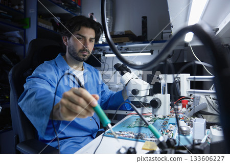 A technician skillfully repairs electronic components with precision tool A technician skillfully repairs electronic components with precision tool 133606227