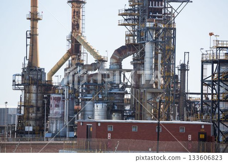 Flat design refinery unit depicting tall distillation towers with pipelines and red-brick building 133606823