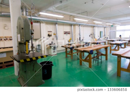 Stationary band saw is standing in flat design workshop showing benches, miter saws, dust ducts 133606858