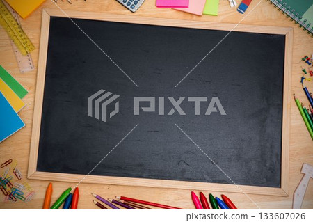 Flat design showing blank chalkboard resting on wooden desk with colored pencils and rulers 133607026