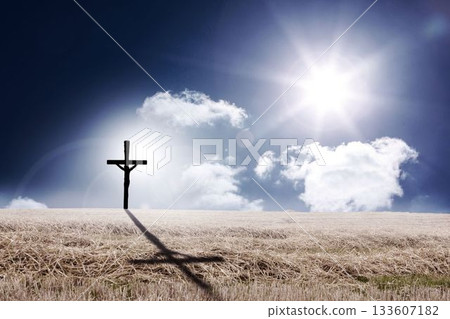 Solitary wooden cross with crucifix standing in harvested wheat under sunlit clouds, casting shadow Solitary wooden cross with crucifix standing in harvested wheat under sunlit clouds, casting shadow 133607182