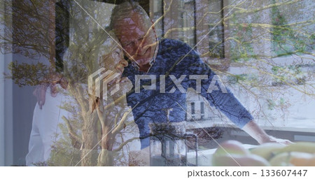 Leaning couple wearing blue sweater and blouse blending home kitchen counter, with tree branches Leaning couple wearing blue sweater and blouse blending home kitchen counter, with tree branches 133607447