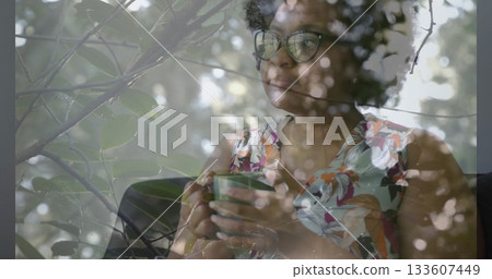 Holding green mug woman wearing floral blouse and glasses gazing at window, copy space Holding green mug woman wearing floral blouse and glasses gazing at window, copy space 133607449