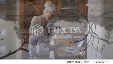 Working mature couple collaborating at home kitchen workspace, with laptop and lakeside reflection Working mature couple collaborating at home kitchen workspace, with laptop and lakeside reflection 133607452