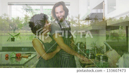 Embracing cooking couple stirring frying pan on stovetop at kitchen island, with tomatoes and herbs 133607473
