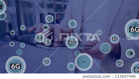 Tapping mature man wearing light blazer holding tablet in corporate plaza, with floating 6G icons 133607496