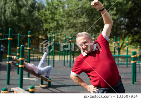 Aged man practicing gymnastics in open-air sports area 133607914