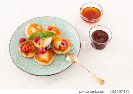 Curd fritters with raspberries, strawberry jam and honey. 133607971