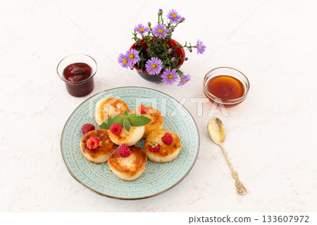 Curd fritters with raspberries, strawberry jam and honey. 133607972