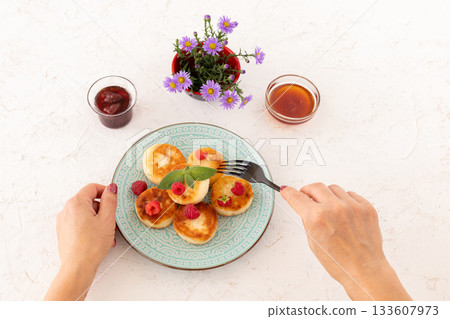 Curd fritters with raspberries, strawberry jam and honey. 133607973