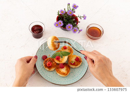 Curd fritters with raspberries, strawberry jam and honey. 133607975