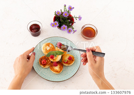 Curd fritters with raspberries, strawberry jam and honey. 133607976