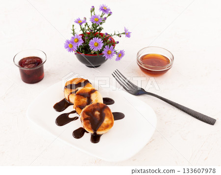 Curd fritters with chocolate, strawberry jam and honey. 133607978