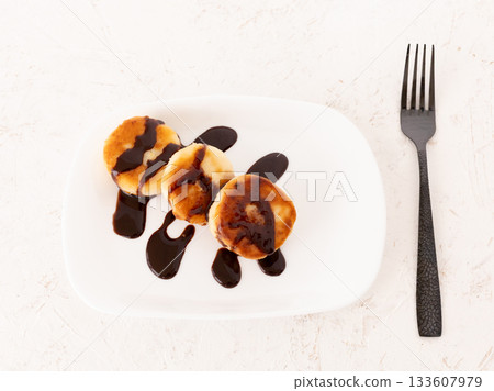 Curd fritters with chocolate on the porcelain plate. 133607979