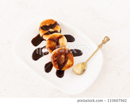 Curd fritters with chocolate on the porcelain plate. 133607982