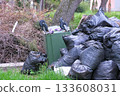 Black garbage bags near and an overturned trash can on the street. 133608031