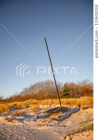 abandoned catamaran on sandy beach at sunset 133608308