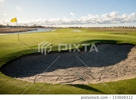 golf course bunker with rake and yellow flag on sunny day golf course bunker with rake and yellow flag on sunny day 133608312