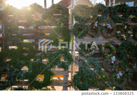 Christmas wreaths displayed on wooden pallet in winter sun Christmas wreaths displayed on wooden pallet in winter sun 133608325