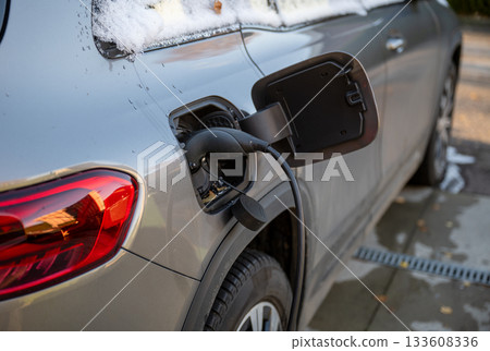 electric car charging in winter driveway 133608336