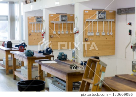 Wooden workbenches featuring bench grinders and loose cables are lining flat design workshop room Wooden workbenches featuring bench grinders and loose cables are lining flat design workshop room 133609096
