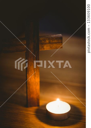 Candle by wooden cross on table Candle by wooden cross on table 133609100