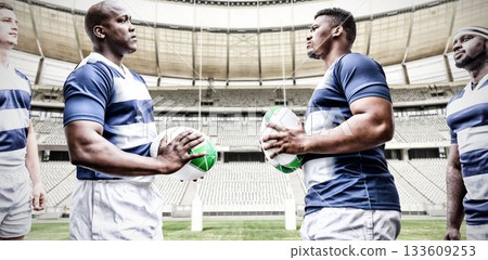 Male rugby players holding ball looking at each other Male rugby players holding ball looking at each other 133609253
