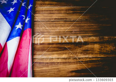 Flat design illustration showing folded American flag draping left side over rustic wooden tabletop 133609303