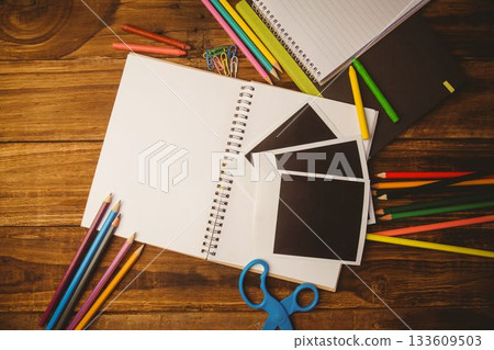Flat design scene is showing spiral notebook on wooden desk with colored pencils, crayons, scissors Flat design scene is showing spiral notebook on wooden desk with colored pencils, crayons, scissors 133609503