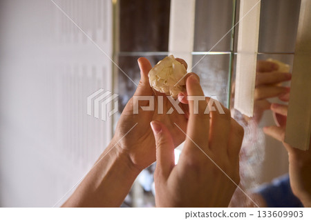 Final touch on reflective surface, Applying sponge to seal mirror tape in home renovation, Using sponge to smooth and seal mirror edge during home makeover process 133609903