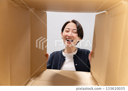 一位微笑的女子正看著紙箱。 133610035