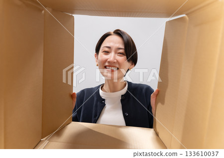 一位微笑的女子正看著紙箱。 133610037