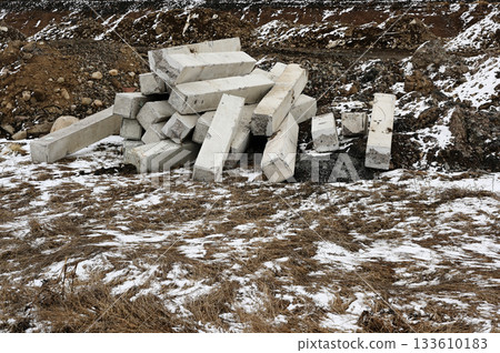 A pile of broken concrete blocks sits abandoned in a rugged, partially snow-covered landscape 133610183
