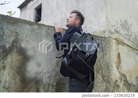 A Curious Young Man Peeking into Someone Yard Through the Fence 133610219