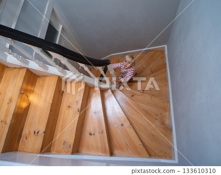 Little 4 year old girl climbing up a steep staircase 133610310