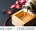 Still life of sake poured into a masu and plum blossoms 133610445
