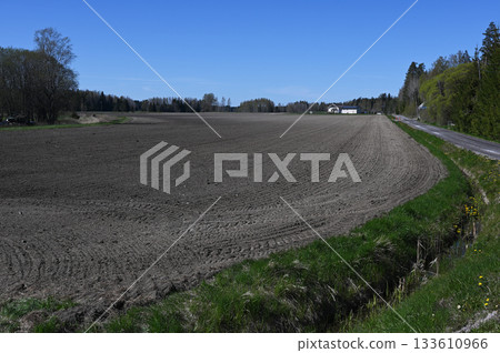 a vast plowed field under a clear blue sky in a peaceful rural setting 133610966