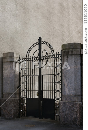 a striking black wrought iron gate with a symmetrical, geometric design dominated by circular patterns and an arched top 133611060