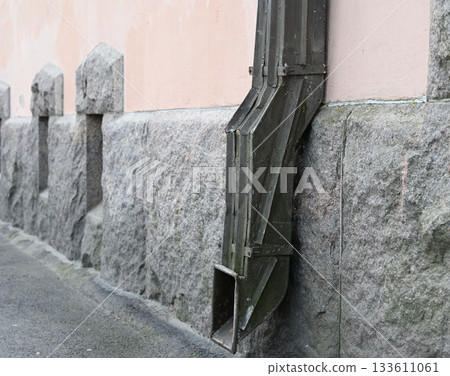 a close-up view of an aged metal rain gutter downspout 133611061